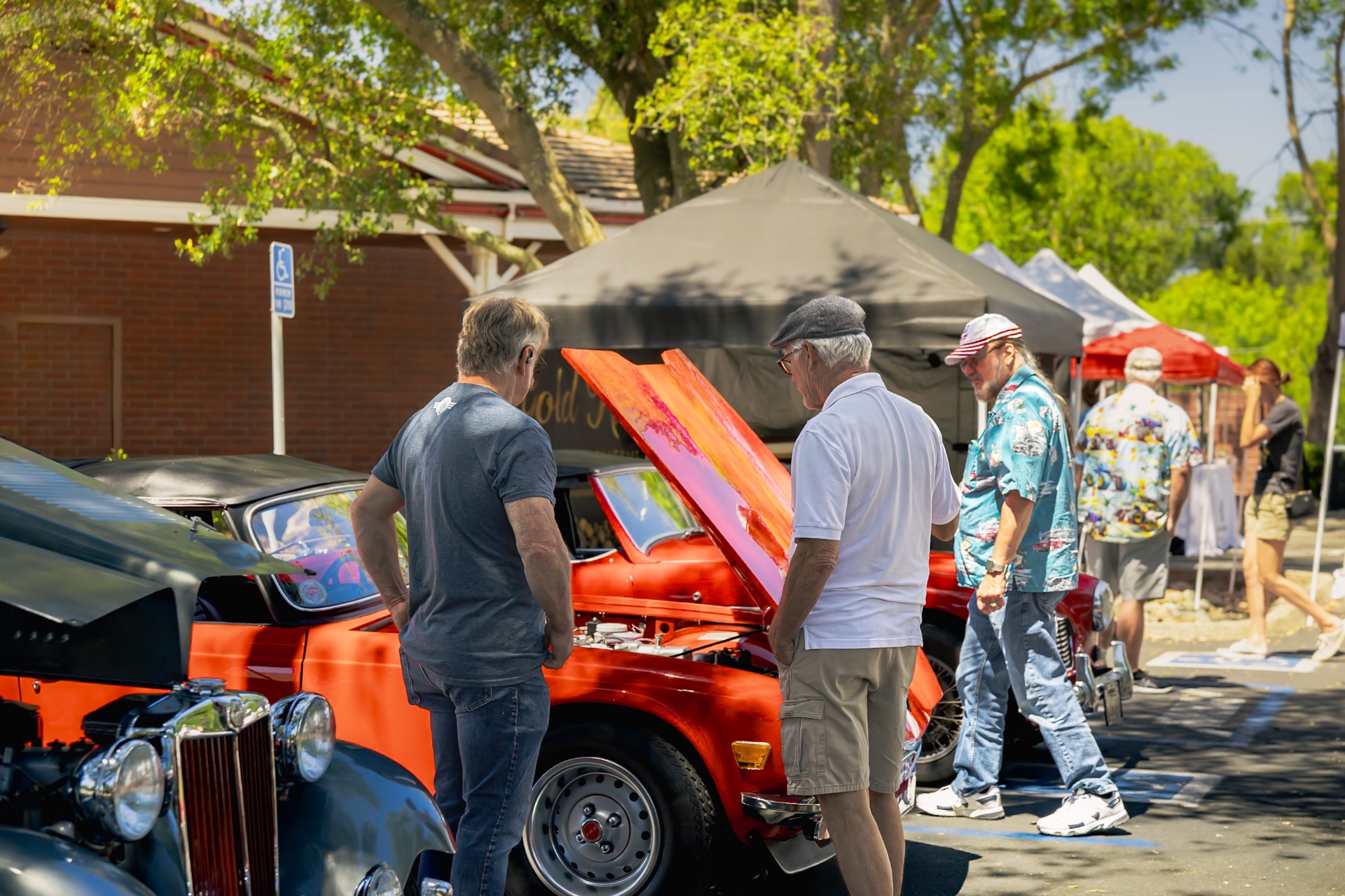 Spectators admiring an orange classic with hood up