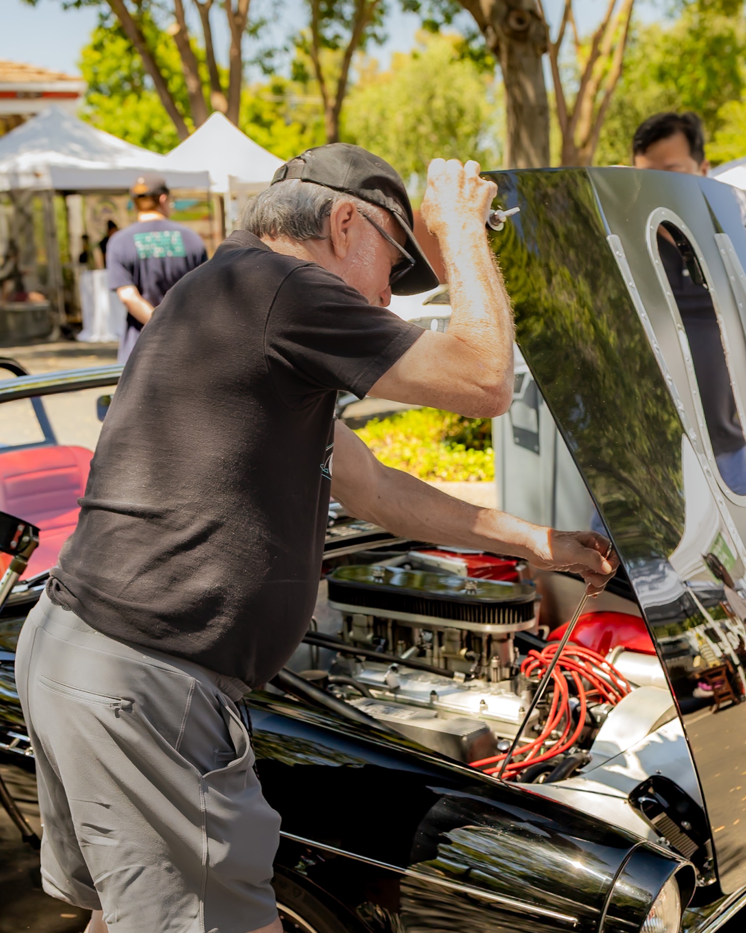 Owner checking the engine of a black classic sports car